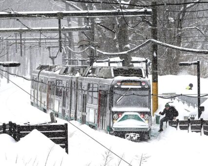 An MBTA green line subway train sits at a station during a winter snow storm.