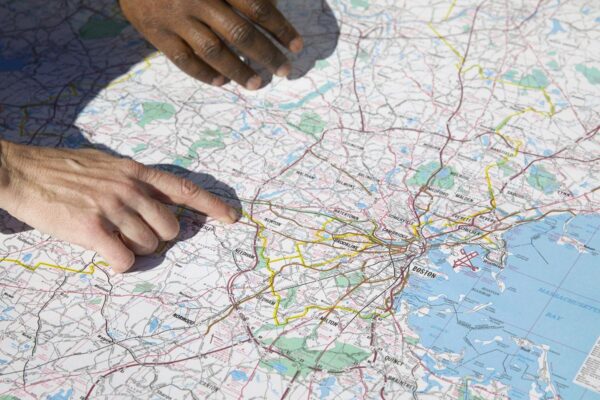 Staff analyzing a Greater Boston map, pinpointing Route 128/Needham—local corridor know-how.