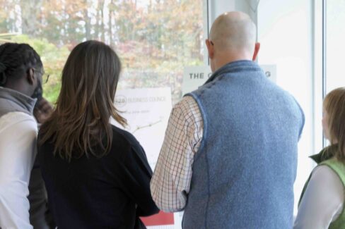 Members of the 128 Business Council reviewing printouts of Grid system data against a fall backdrop.