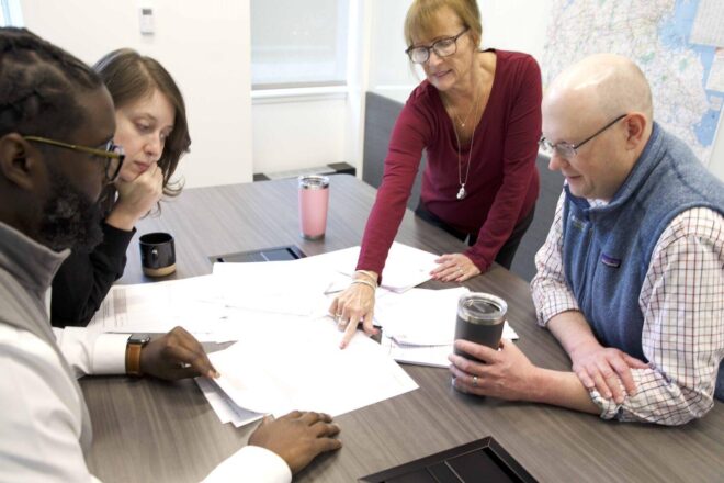 Members of the 128 Business Council team review data at a conference room table.