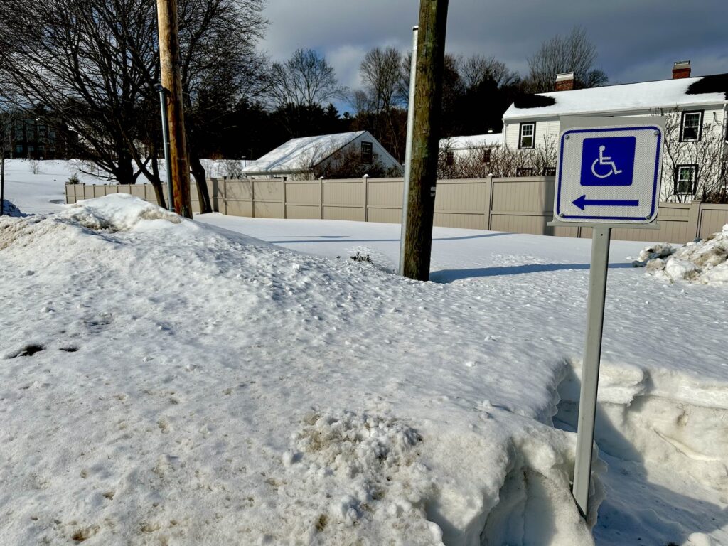 Sign indicating wheelchair access points directly into a snow mound.