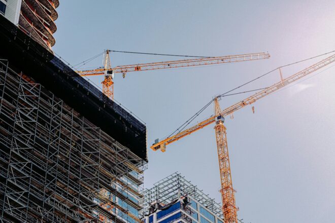 Cranes reaching over a partially constructed building