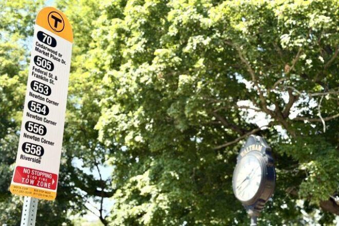 MBTA Bus Stop Sign showing routes including Express Route 505, with Waltham Center clock in the background
